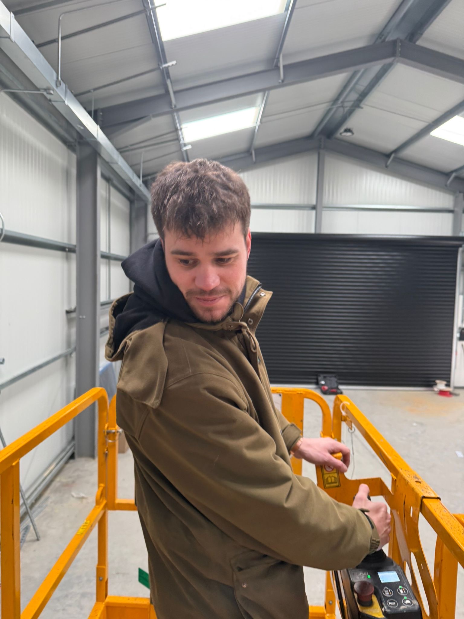 Electrician controlling a cherry picker at an industrial garage.