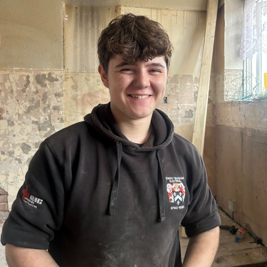 Smiling electrical apprentice on commercial site.