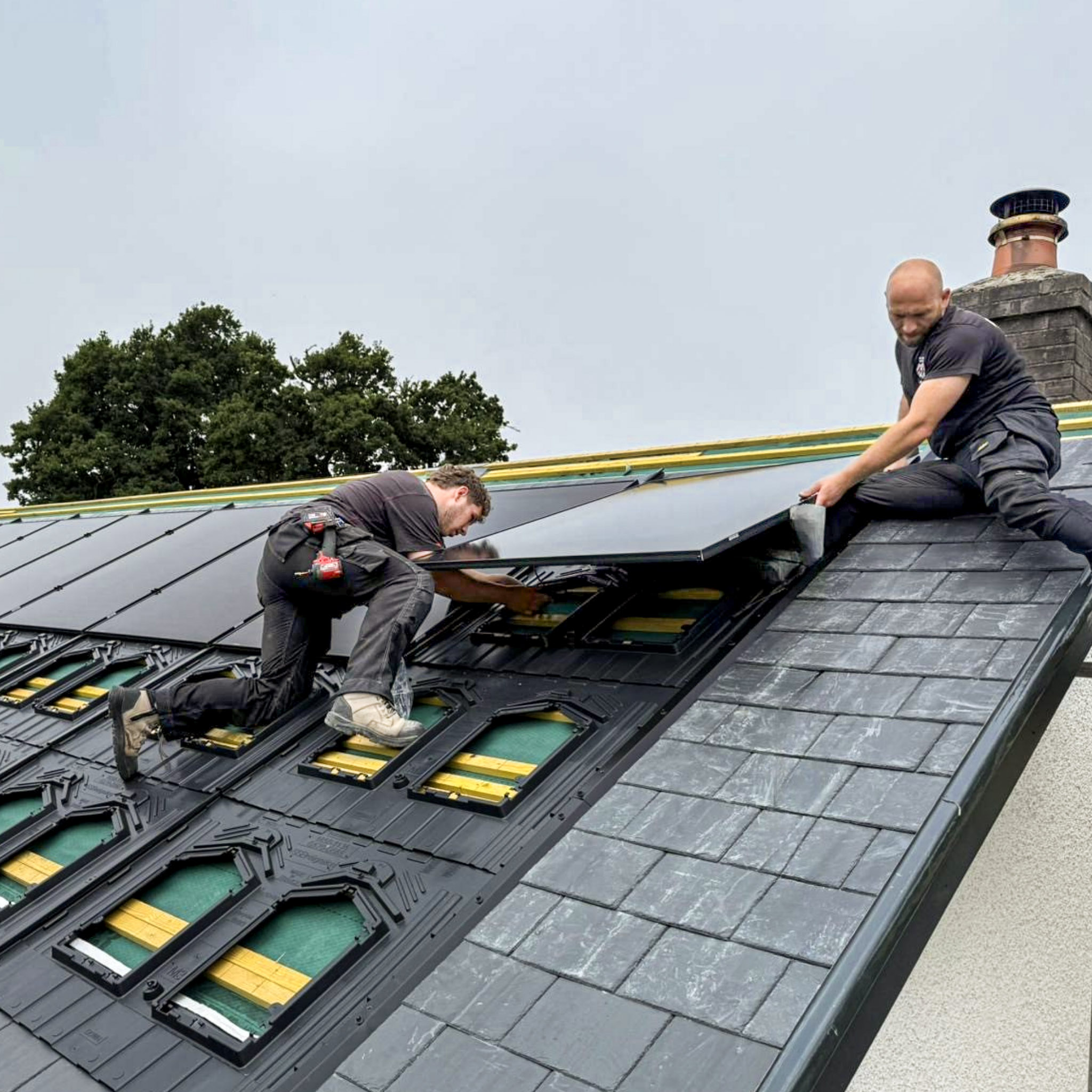 Home Electricians on top of a roof in the process of installing a row of solar panels.
