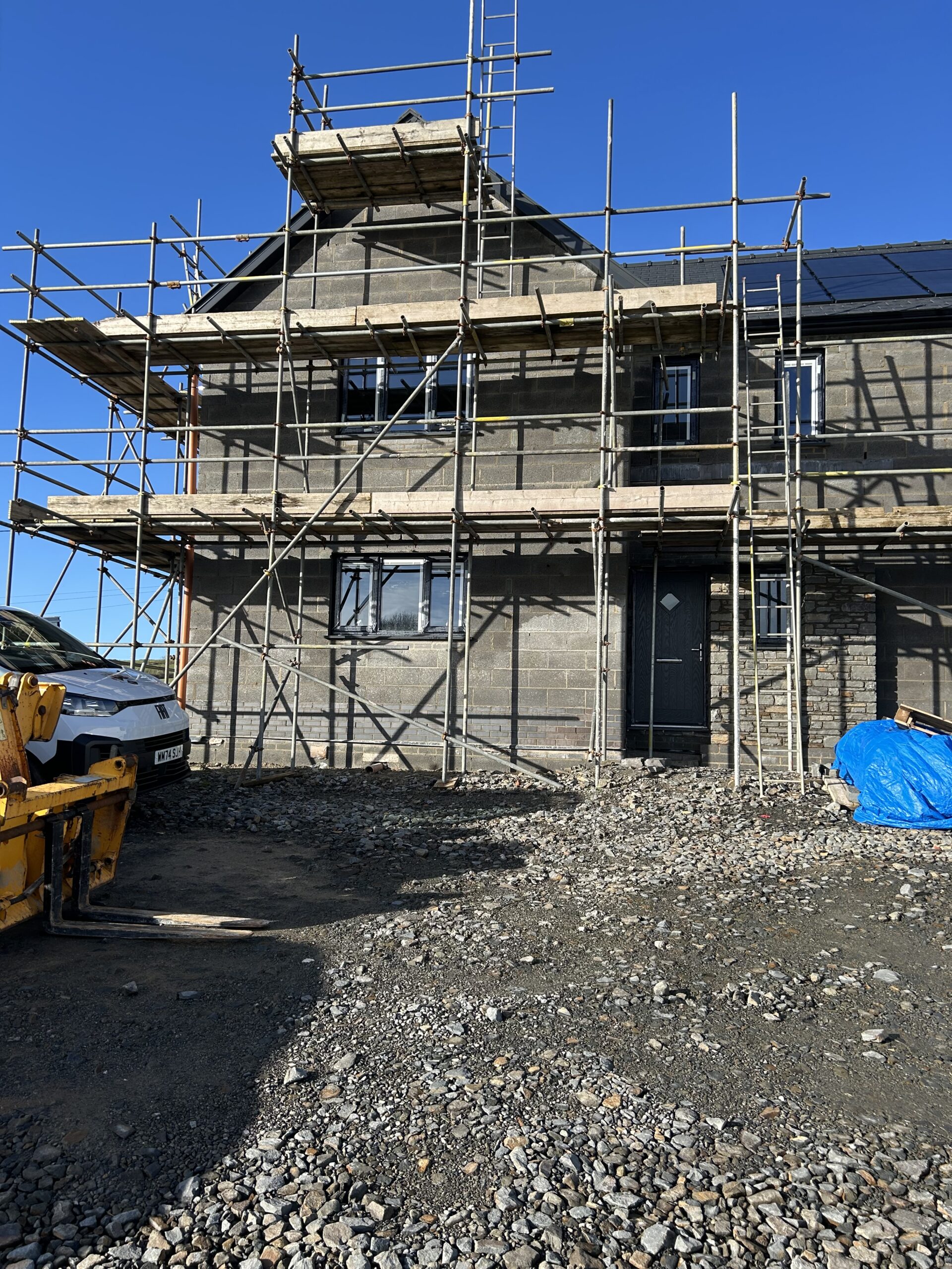 Large house in the middle of construction, covered in scaffolding.