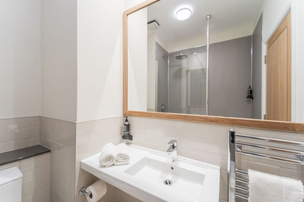 Modern hotel bathroom with bright lighting, clean white sink below the mirror.