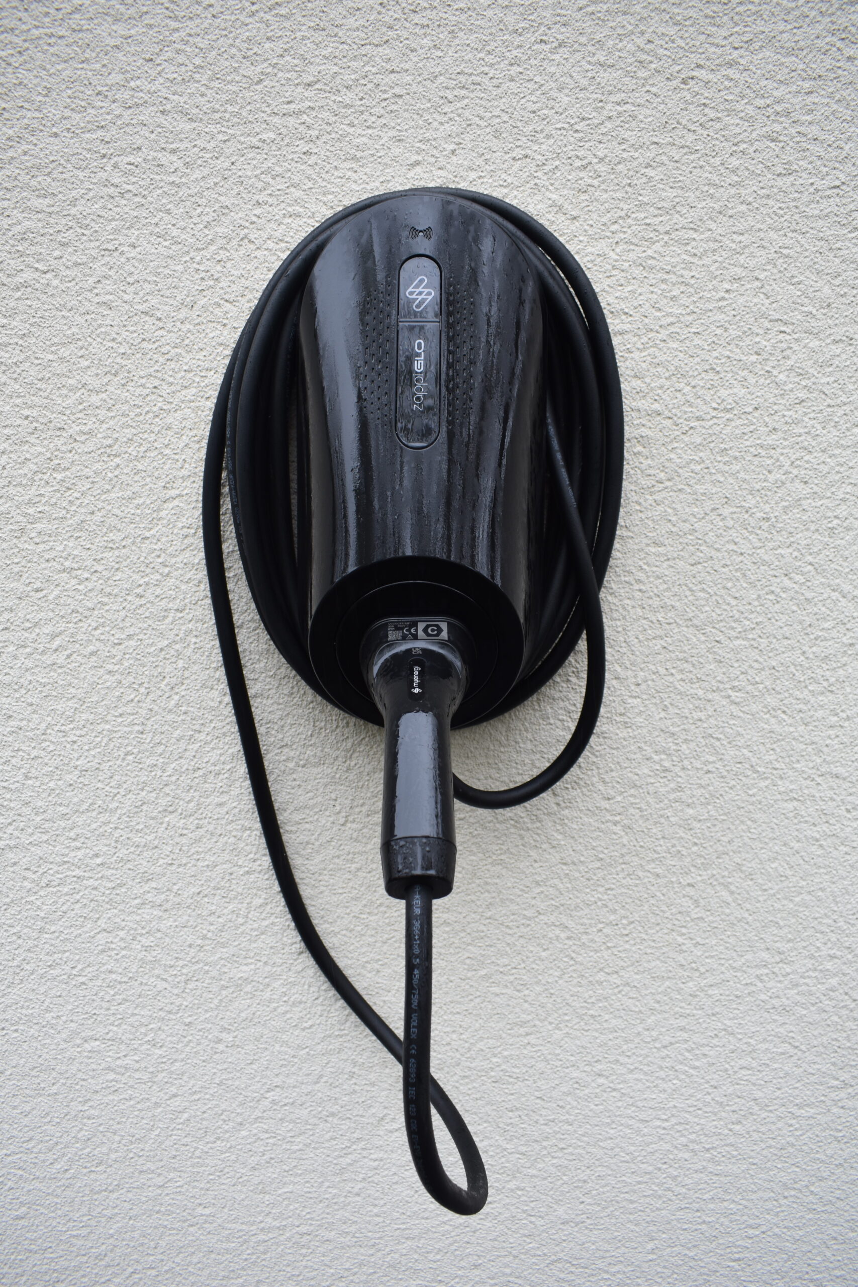 A balck MyEnergi Zappi Glo charger installed on an exterior wall