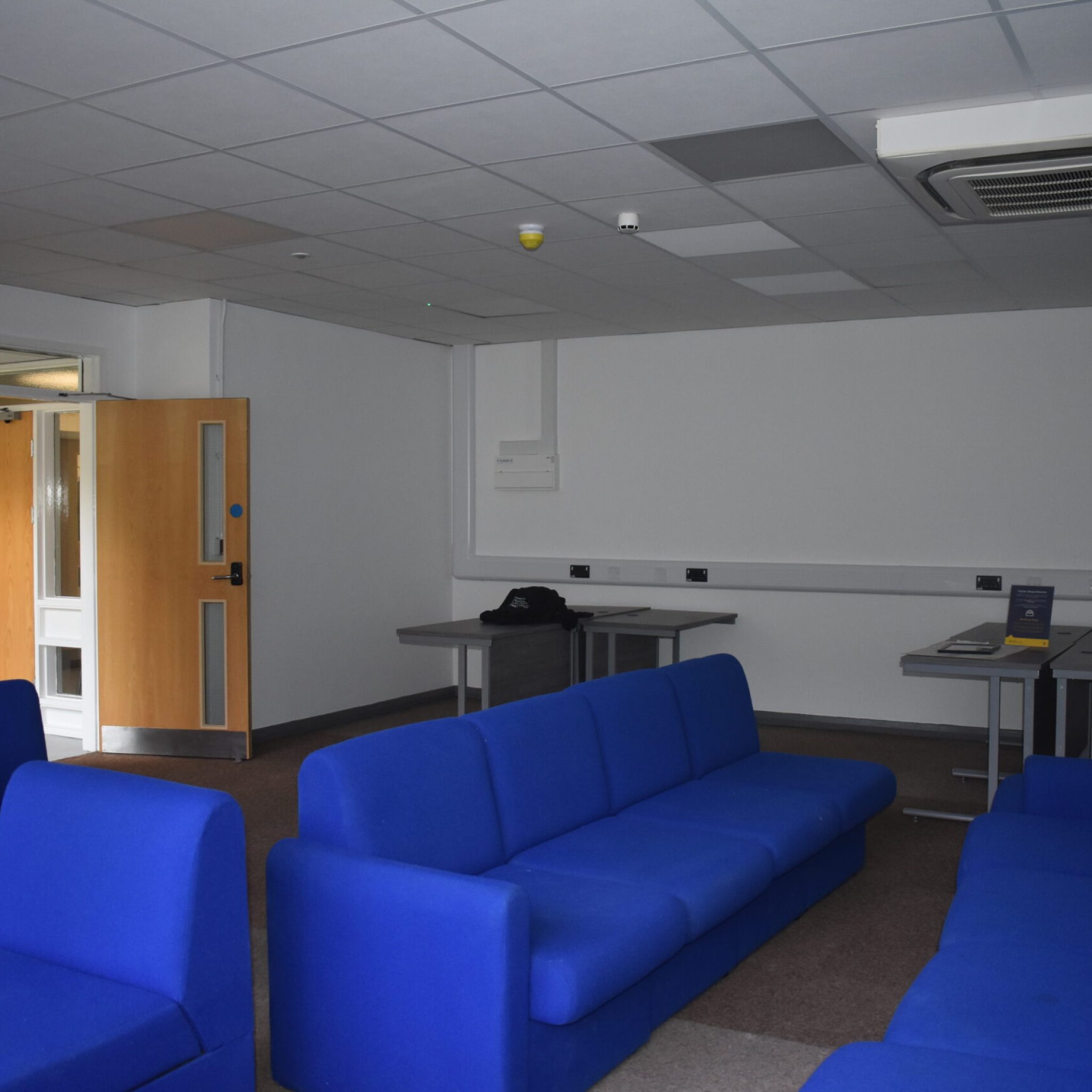 Office in Aberystwyth University building. There are four blue sofas in the middle of the room.